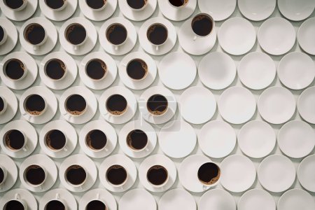 Téléchargez les photos : Un plan aérien plein cadre présentant un motif symétrique de tasses à café blanches remplies de café noir, méticuleusement alignées sur un fond texturé, mettant en évidence l'ordre et le design. - en image libre de droit
