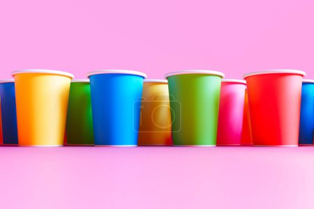 Téléchargez les photos : Parfaitement alignées, les tasses en plastique jetables multicolores sont disposées sur un fond rose vif, illustrant un mélange de commodité et de célébration en un seul coup d'œil. - en image libre de droit