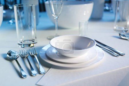 Téléchargez les photos : Table à manger somptueuse avec couverts en argent poli, verres en cristal étincelant et élégantes assiettes en porcelaine blanche, prête pour un banquet ou un gala sophistiqué. - en image libre de droit