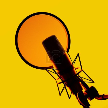 Una perspectiva elevada muestra un micrófono de estudio profesional con un filtro pop, ubicado sobre un llamativo fondo amarillo, ideal para grabación de audio de alta fidelidad, podcasting y trabajo de voz..