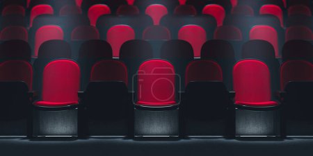 Téléchargez les photos : Un seul siège de théâtre rouge s'illumine sous les projecteurs, distinct parmi les rangées de chaises noires vides dans un cinéma autrement sombre, évoquant un sentiment d'anticipation et d'exclusivité. - en image libre de droit