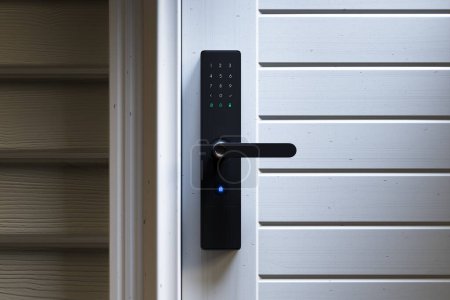 Sorgfältiger Blick auf ein fortschrittliches digitales Türschloss mit Ziffernblock an einer Holztür, das für anspruchsvolle Sicherheit und modernes Wohnen steht.