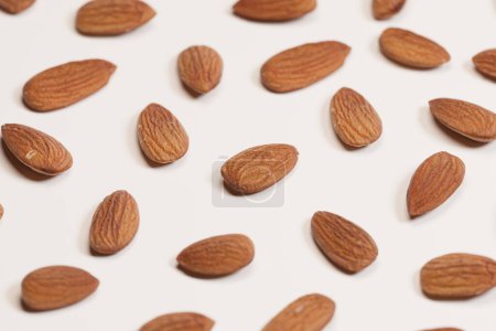 Photo for An elegant display of fresh, unprocessed almonds lies scattered across a bright white background, creating a stunning visual of simplicity and organic appeal. - Royalty Free Image