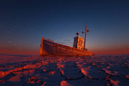 Photo for Scene portraying an abandoned boat lying on parched soil juxtaposed with the ethereal beauty of a star-dappled twilight backdrop, exuding a sense of forgotten stories amidst natural splendor. - Royalty Free Image