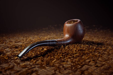 Photo for A close-up view showcases the fine details of a vintage mahogany pipe atop a bed of loose, fragrant tobacco leaves, reflecting a longstanding tradition of tobacco enjoyment. - Royalty Free Image