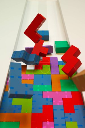 Foto de Imagen cautivadora de bloques de juegos 3D multicolores en un animado descenso, que ilustra el impulso y el contraste lúdico sobre un fondo blanco. - Imagen libre de derechos