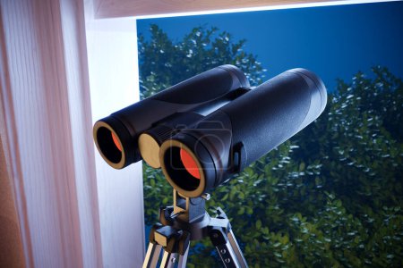 Photo for A detailed view of sleek, powerful binoculars on a sturdy tripod overlooking a dense green landscape, suggesting wildlife observation or secretive monitoring activities. - Royalty Free Image