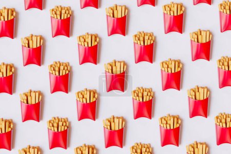 Photo for A neatly organized array of red French fry cartons creates a striking, repetitive pattern, evoking fast food themes; perfect for design and culinary graphics. - Royalty Free Image