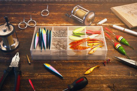 Close-up view of a diverse fishing tackle collection spread on a weathered wooden table, featuring an assortment of multicolored lures and angling equipment.