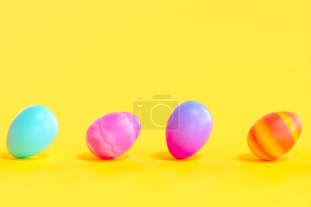 Téléchargez les photos : Arrangement festif de divers œufs de Pâques peints alignés soigneusement sur un fond jaune ensoleillé, créant un affichage saisonnier parfait rempli de couleur et de tradition. - en image libre de droit