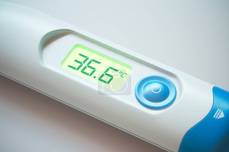 High-resolution close-up on a digital thermometer with a 36.5C readout, indicating a normal body temperature against a clinical background
