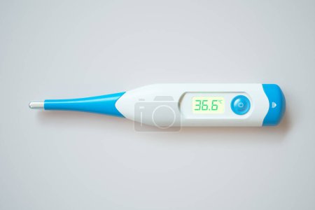 Téléchargez les photos : Thermomètre médical numérique de haute précision affichant une température corporelle normale de 36,6C, élégamment isolé sur un fond blanc pur, symbolisant la précision dans la surveillance de la santé - en image libre de droit