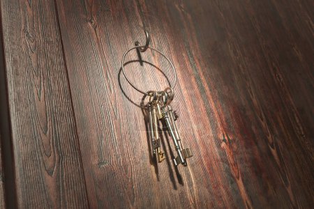 Photo for An intricately arranged assortment of aged metal keys lie atop an old wooden surface, evoking a sense of nostalgia and the passage of time with their historical charm. - Royalty Free Image