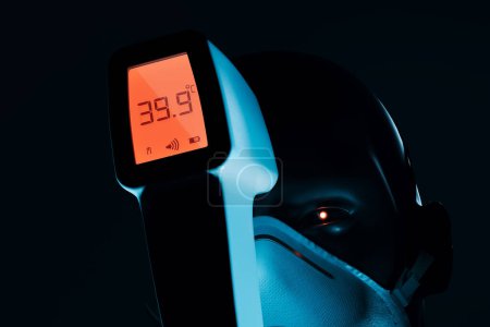 Foto de Una persona que usa una mascarilla facial se somete a una verificación de temperatura con un termómetro infrarrojo digital, revelando síntomas de fiebre alta en un entorno clínico.. - Imagen libre de derechos
