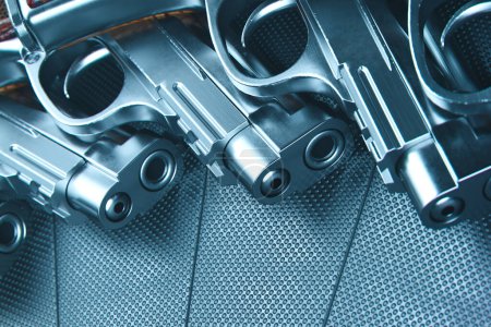 Un affichage rapproché avec plusieurs revolvers argentés sur une texture pointillée métallique distinctive, mettant en évidence l'artisanat complexe et les détails de conception en métal armé.