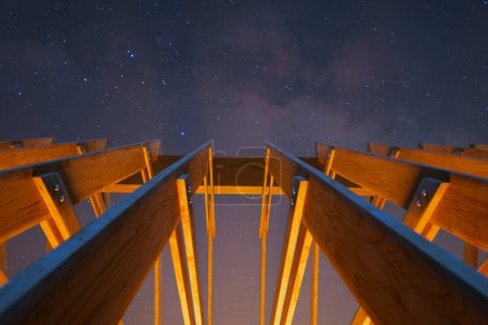 Foto de Captura cautivadora desde un ángulo bajo muestra la silueta cruda de una estructura de madera que abarca la impresionante extensión llena de estrellas de los cielos nocturnos. - Imagen libre de derechos