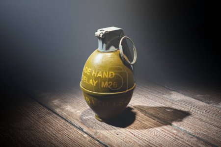 Dramáticamente iluminada, esta granada de mano M26 coleccionable, con su distintiva palanca y pasador de seguridad, se asienta sobre una superficie de madera rugosa, exudando importancia histórica y militar.