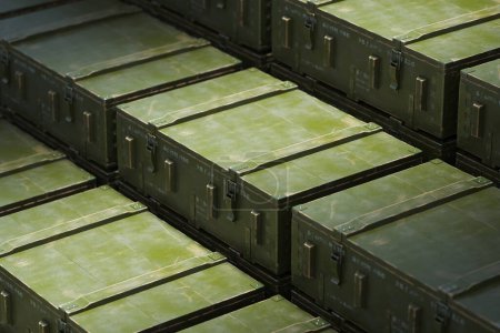 Rows of olive green military ammo boxes are stacked systematically, highlighting the efficiency and organization in military equipment storage and logistics.