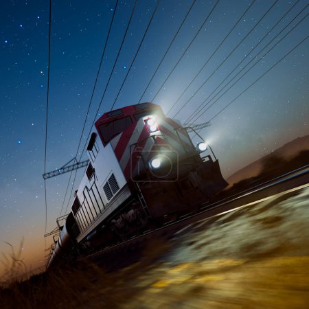 Téléchargez les photos : Capturée la nuit, cette image saisissante montre un train de marchandises traversant le paysage, son chemin éclairé par la lueur de son phare et les étoiles scintillantes au-dessus. - en image libre de droit