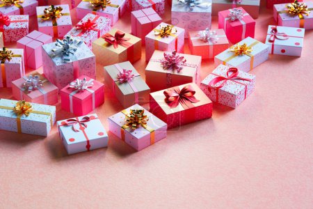 Photo for A stunning display of variously patterned gift boxes with bows, meticulously arranged on a pink textured backdrop, evoking a festive and celebratory atmosphere. - Royalty Free Image