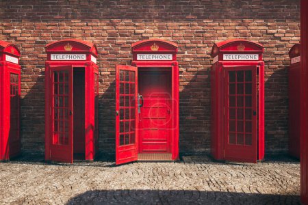 Téléchargez les photos : Une rangée pittoresque de cinq cabines téléphoniques britanniques emblématiques se dresse dans une ligne harmonieuse contre un mur de briques vieilli, avec le soleil de l'après-midi projetant d'élégantes ombres sur la rue pavée ci-dessous. - en image libre de droit
