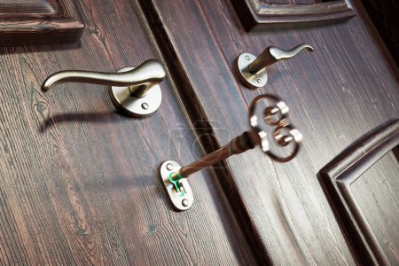 Téléchargez les photos : Gros plan d'une clé vintage intemporelle posée dans la serrure d'une porte en bois élégamment détaillée, mettant en valeur une fusion harmonieuse de charme antique avec une poignée élégante et contemporaine. - en image libre de droit
