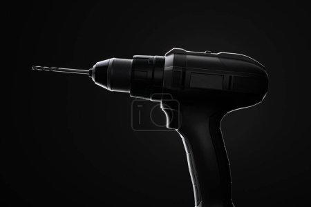 Photo for Detailed silhouette of a cordless drill on a dark gradient backdrop, showcasing the tool's design, form, and the potential for versatile usage in construction and DIY projects. - Royalty Free Image