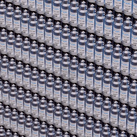 Una amplia y ordenada exhibición de latas de aerosol metálicas plateadas con llamativas etiquetas azules, dispuestas en filas perfectas dentro de un entorno industrial, mostrando la producción en masa.