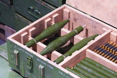 Téléchargez les photos : Vue détaillée des munitions militaires organisées, y compris les obus d'artillerie verts et les balles, entreposées solidement dans des caisses en bois robustes, préparées pour le transport. - en image libre de droit