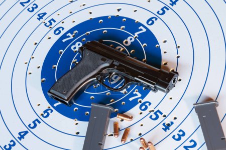 Close-up view of a semi-automatic pistol and a perforated paper target at a shooting range, depicting the concepts of shooting accuracy, firearms proficiency, and safety.