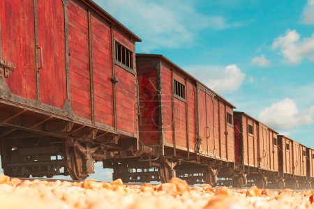 Antike karminrote Eisenbahnwaggons, die auf rostigen Gleisen balancieren und an vergangene Bahnreisen erinnern, stehen in scharfem Kontrast zum riesigen azurblauen Himmel über uns und lassen vergangene Abenteuer erahnen..