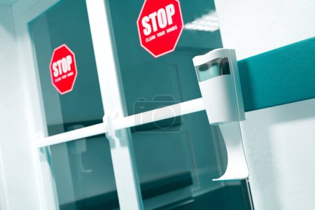 Téléchargez les photos : Promouvoir une hygiène sécuritaire à l'entrée d'un bâtiment, cette photo capture un distributeur automatique de désinfectant pour les mains jumelé à un signe audacieux "STOP : Clean Your Hands". - en image libre de droit