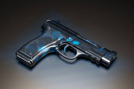 Photo for Exquisitely designed handgun with bold blue accents prominently displayed against a dark, mysterious surface, highlighting its modern aesthetic and superior craftsmanship. - Royalty Free Image