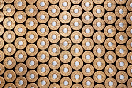 Photo for An expansive, detailed visual of uniformly arranged shotgun shells, showcasing their metallic textures and colors in a symmetrical full-frame pattern. - Royalty Free Image