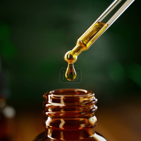 Cette macro photographie capture le moment précis où une gouttelette d'huile visqueuse dorée est suspendue à la pointe d'une pipette en verre transparent, contrastée par un fond vert doux..