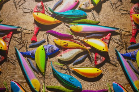 Téléchargez les photos : Une sélection accrocheuse de leurres de pêche présentés dans des couleurs vives, chacun méticuleusement placé sur une toile de fond grossière, soulignant la diversité dans la forme et la fonction pour les amateurs de pêche. - en image libre de droit