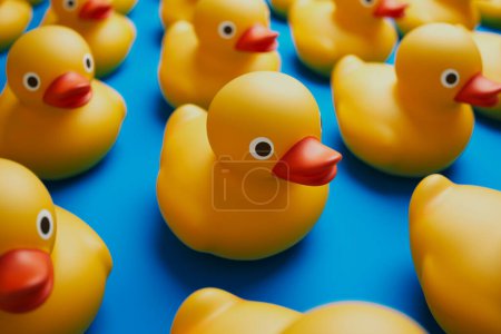 A playful arrangement of numerous yellow rubber ducks stands out on a striking blue background, symbolizing joy, childhood innocence, and the simplicity of playful design elements.