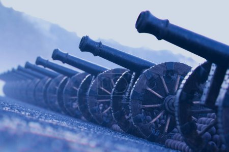 Téléchargez les photos : Un tableau évocateur de canons anciens d'une époque militaire révolue, méticuleusement disposés sur un ancien chemin pavé, enveloppés par une ambiance sombre et nuageuse. - en image libre de droit