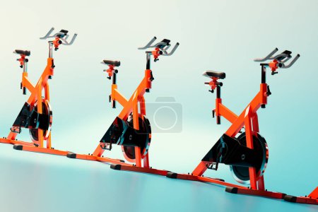 Foto de Un trío de bicicletas giratorias estacionarias de color naranja brillante está en perfecta alineación sobre un fondo azul degradado profundo, personificando una mezcla de fitness de alta energía y estética de diseño moderno. - Imagen libre de derechos