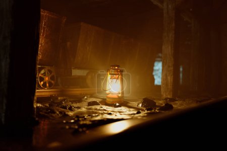 Téléchargez les photos : Une lanterne antique irradie une chaleur apaisante au milieu de l'obscurité étrange d'un tunnel minier historique, évoquant l'époque révolue des labeurs des mineurs. - en image libre de droit
