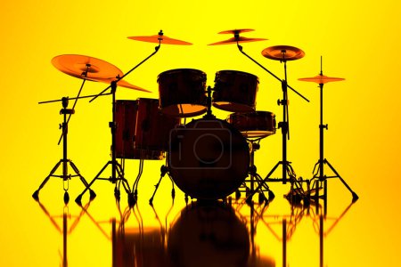 Foto de Una silueta visualmente llamativa de un conjunto de tambores destaca con un marcado contraste contra un vivo fondo amarillo, exudando energía musical y ritmo en una representación artística. - Imagen libre de derechos