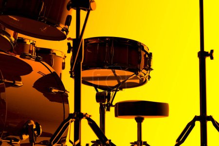 Téléchargez les photos : Une silhouette accrocheuse et contrastée d'un ensemble de tambours professionnels, présentée sur un fond jaune vif, soulignant le contour détaillé de l'instrument de musique. - en image libre de droit