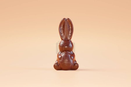 Téléchargez les photos : Cette image capture un lapin en chocolat brillant posé sur un fond couleur pêche, illustrant l'attrait d'un bonbon de Pâques traditionnel.. - en image libre de droit