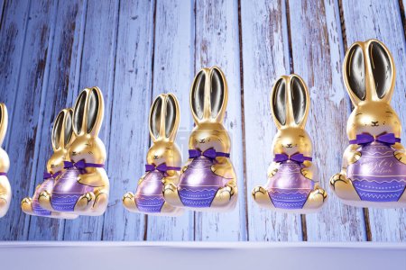 Téléchargez les photos : Découvrez un ensemble captivant de six figurines de lapin de Pâques dorées et brillantes, chacune agrémentée d'un élégant ruban violet, disposées habilement sur une surface en bois texturée. - en image libre de droit