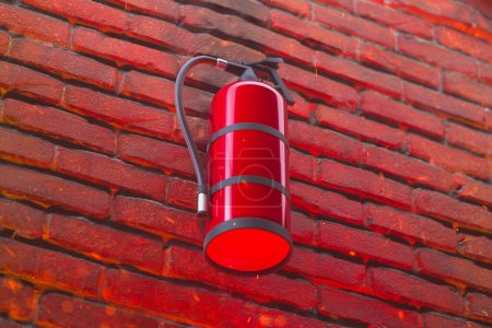 Photo for Close-up image showcasing a vibrant red fire extinguisher securely fixed against a textured brick wall, epitomizing readiness and safety measures for fire emergencies. - Royalty Free Image