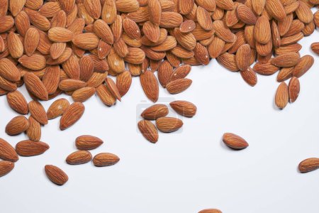 Photo for High-resolution photo showcasing an abundance of whole, natural almonds spread erratically on a white backdrop, ideal for showcasing in food and health-related concepts. - Royalty Free Image
