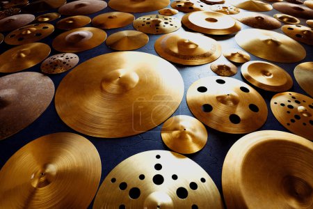 Una selección cuidadosamente organizada de varios tipos de platillos, cada uno mostrando acabados únicos y perforaciones, colocados sobre un fondo oscuro, que ilustra la diversidad de instrumentos de percusión.