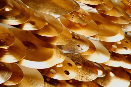 Téléchargez les photos : Plan rapproché exquis d'un assortiment de cymbales en laiton, leurs perforations capturant la lumière du soleil, soulignant la texture et la brillance destinées à un usage musical professionnel. - en image libre de droit
