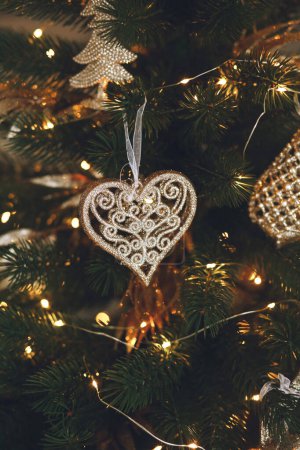 Photo for Christmas toy in the shape of a heart. Christmas tree decorated with beautiful golden toys on beautiful holiday background, copy space for text. Christmas and New Year concept, greeting card - Royalty Free Image