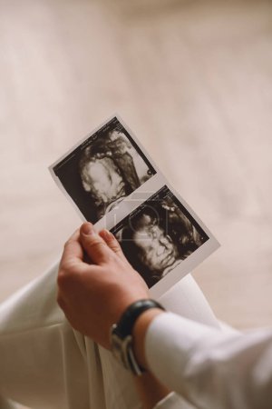 Close up photo of pregnant woman and her husband holding the ultrasound picture. Copy space for text. The concept of happy parenthood